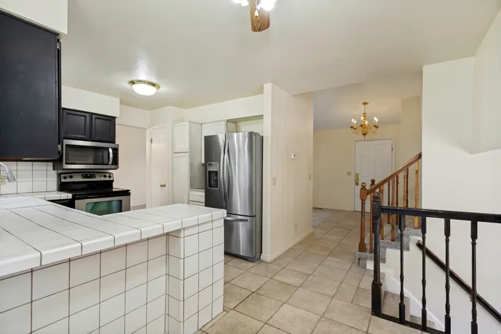 Kitchen featuring tile countertops, stainless steel appliances, and dark cabinetry