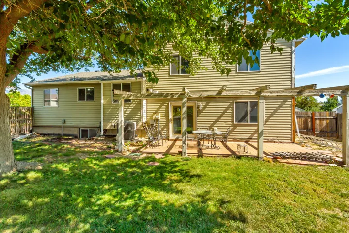 Back of property - Expansive backyard featuring a manicured lawn, a wooden deck, and a pergola structure