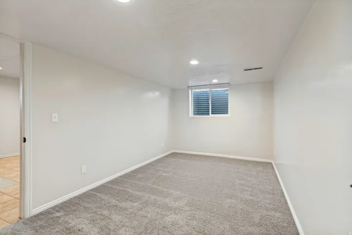 ADU - Carpeted room featuring a white window with horizontal blinds, recessed lighting, and a neutral color palette