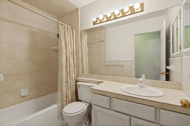 Secondary - Bathroom featuring a vanity with an integrated sink, built-in medicine cabinets, full-width mirror, and a tub with a tile surround