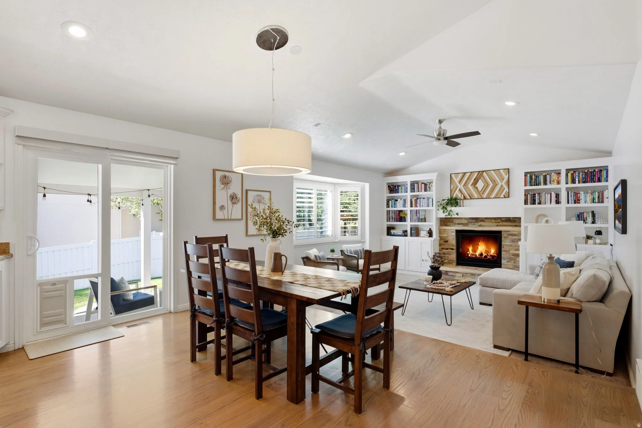 Hardwood-finish flooring, recessed lighting, and a stone-surround fireplace with a wood mantle