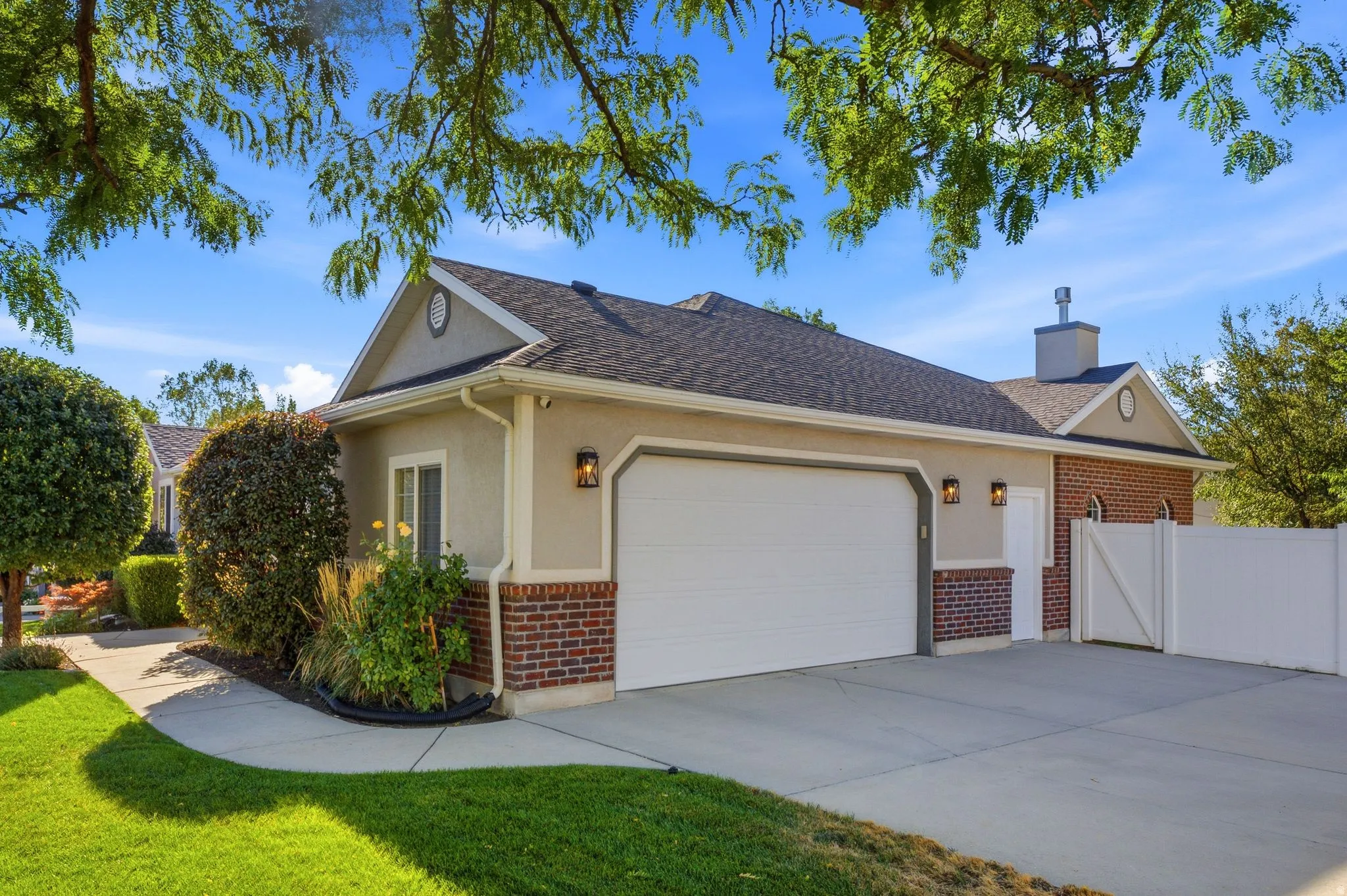 Exterior featuring brick accents, attached garage, concrete driveway, and a white privacy fence