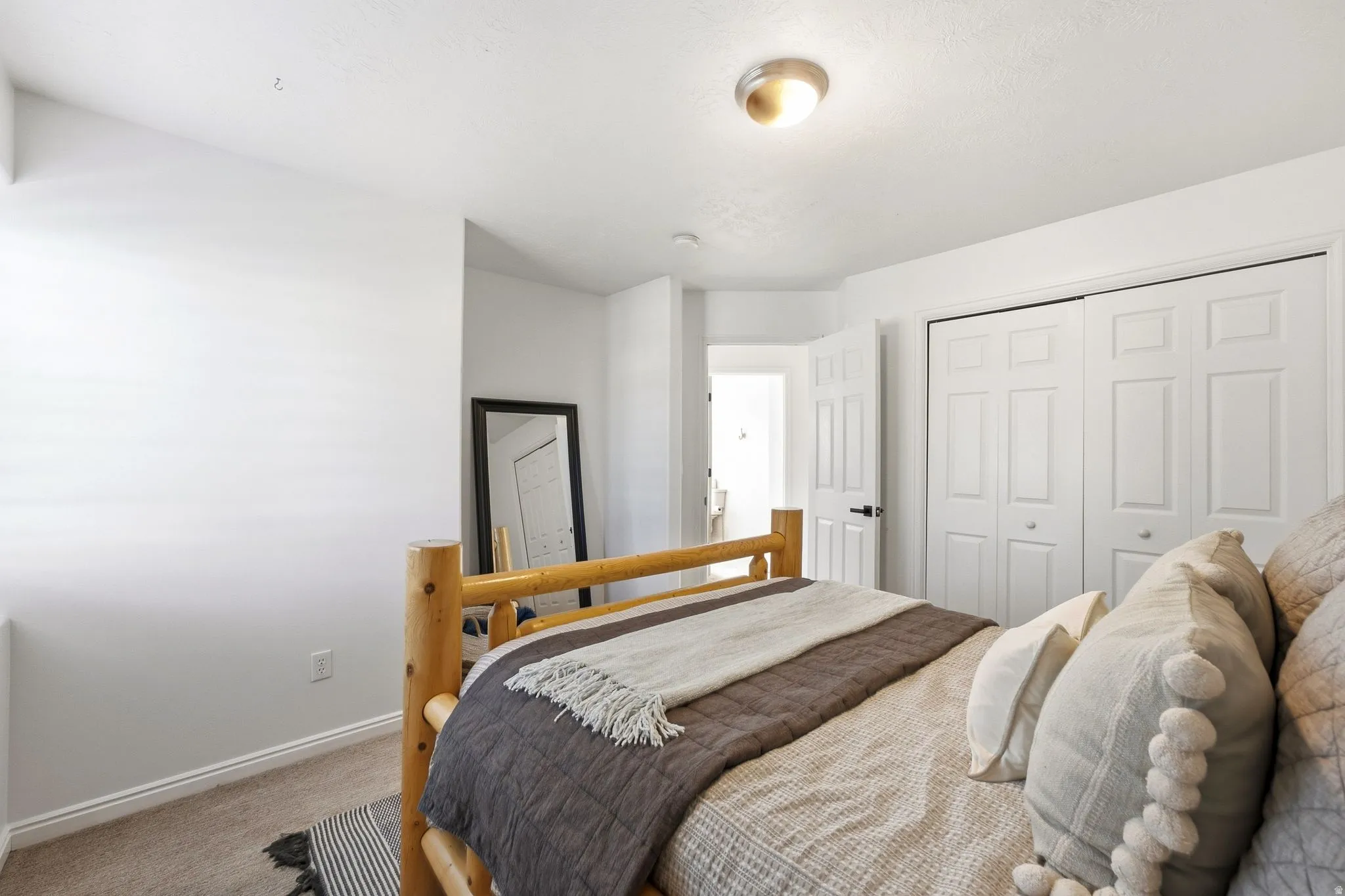 Carpeted flooring, white interior walls, white bi-fold closet doors, and an overhead flush-mount light fixture