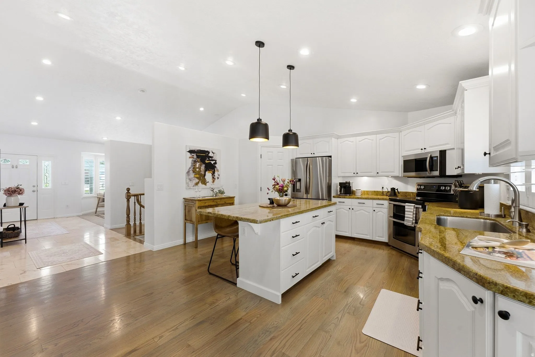 Kitchen featuring wood-finish flooring, white cabinetry, a center island with countertop, and stainless steel appliances