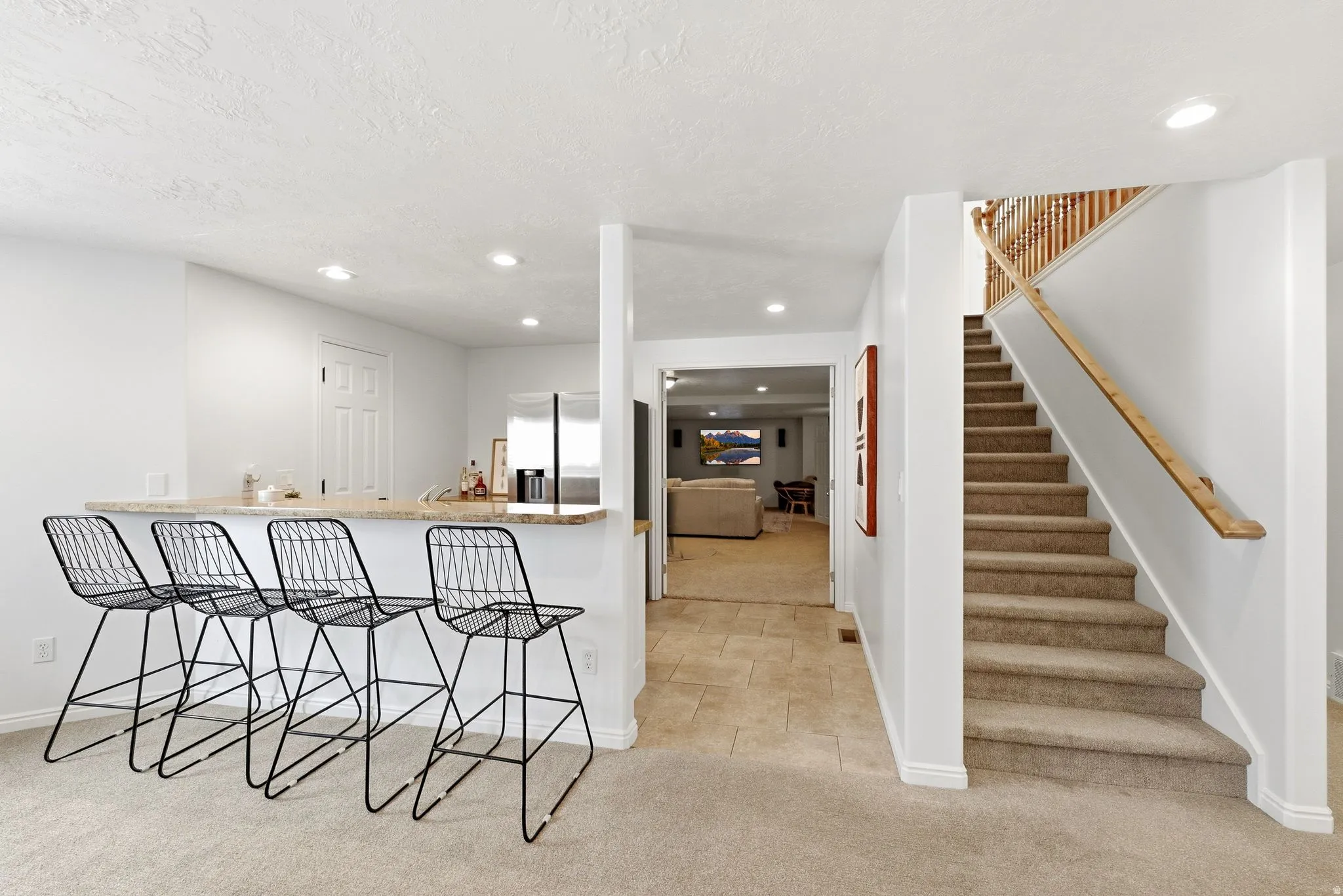 Built-in bar with stone-finish countertop, recessed lighting, and a carpeted staircase with wood handrails