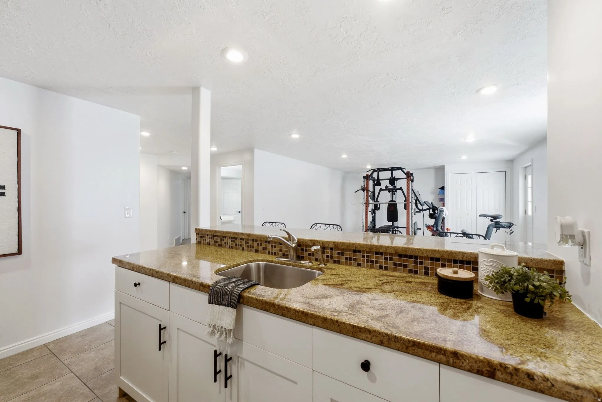 Kitchenette featuring a stainless steel sink, granite-style countertop, mosaic tile backsplash, and recessed lighting