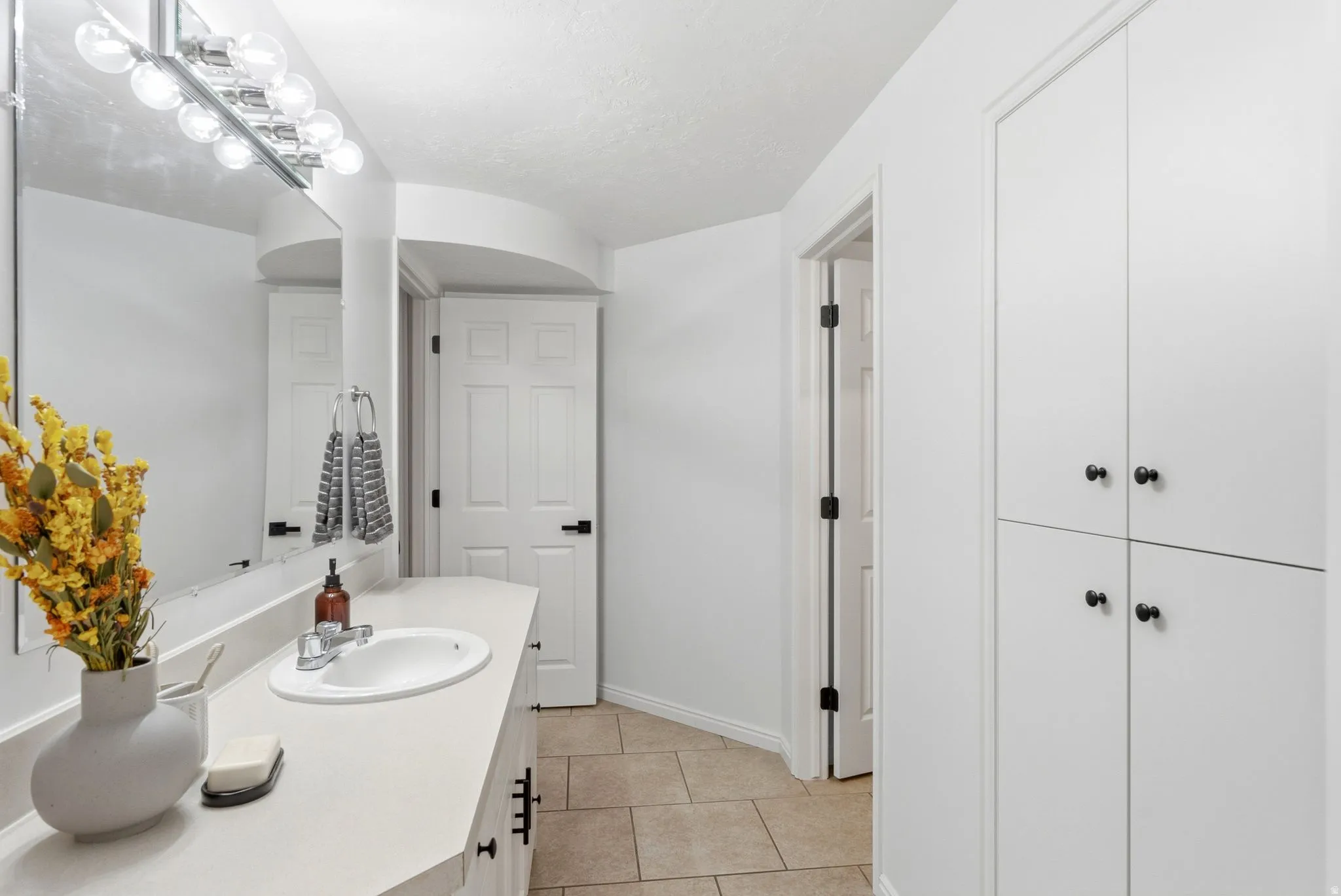 Vanity with an integrated sink, polished chrome faucet, and overhead bar lighting