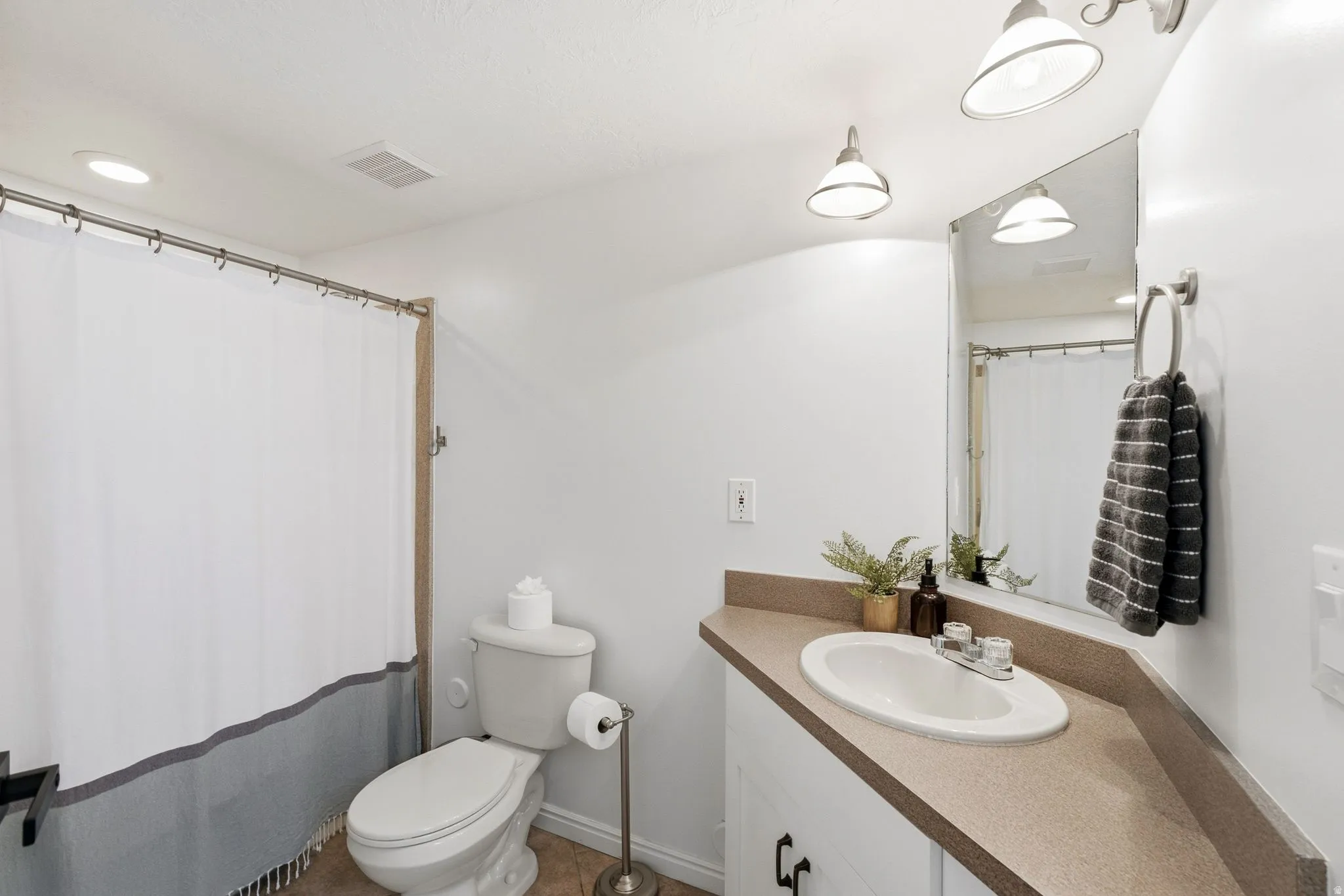 Bathroom featuring a vanity with a drop-in sink, wall-mounted mirror, and overhead lighting