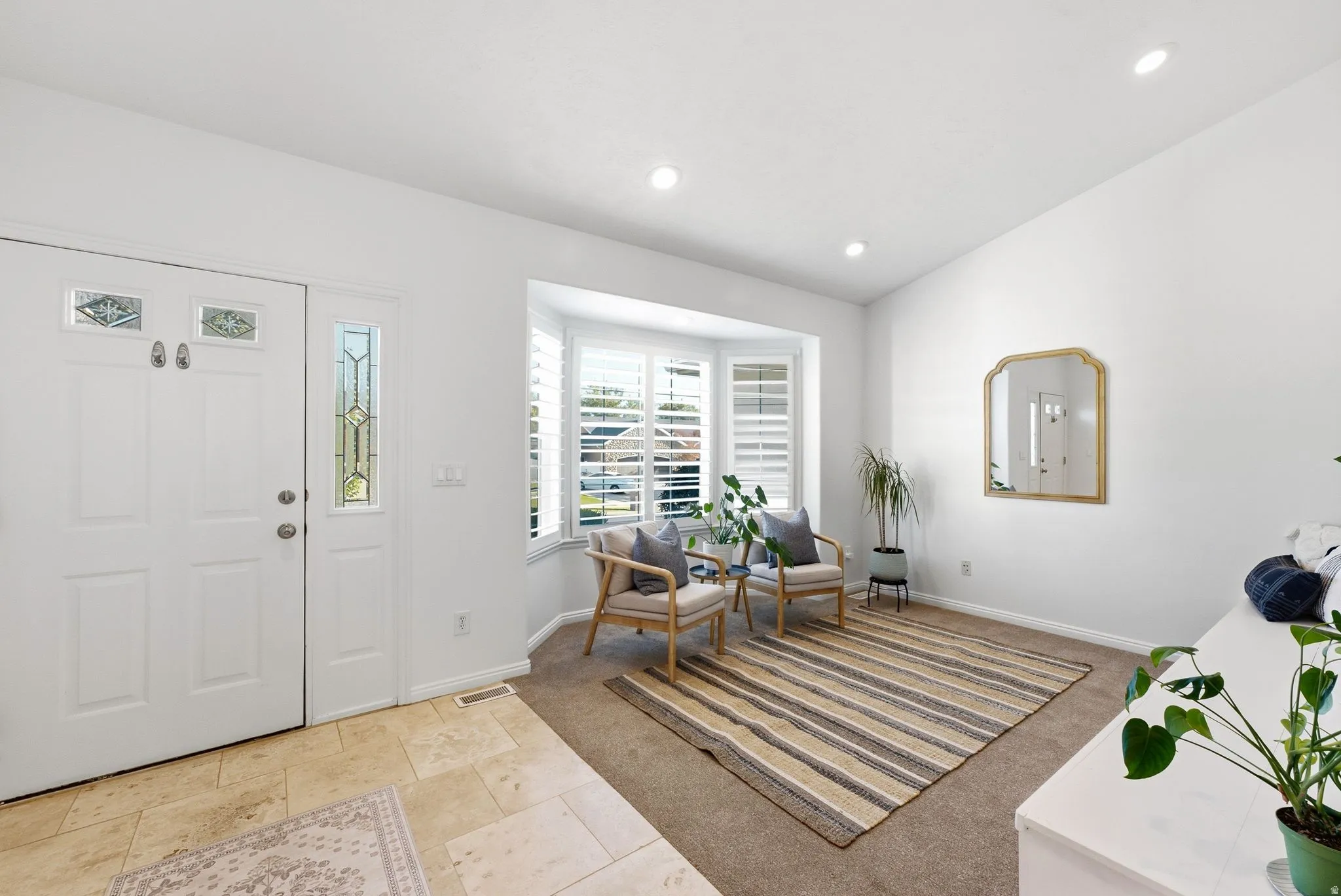 Entryway with a double door featuring decorative glass inserts and a sidelight, tile flooring, recessed lighting, and a bay window with plantation shutters