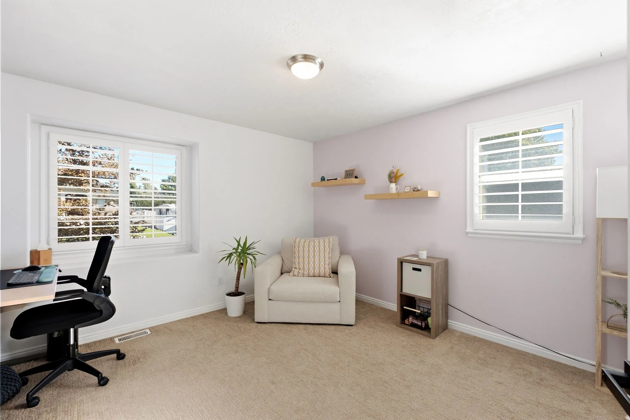 Carpeted flooring, white walls, two windows with plantation shutters, and a flush mount ceiling light