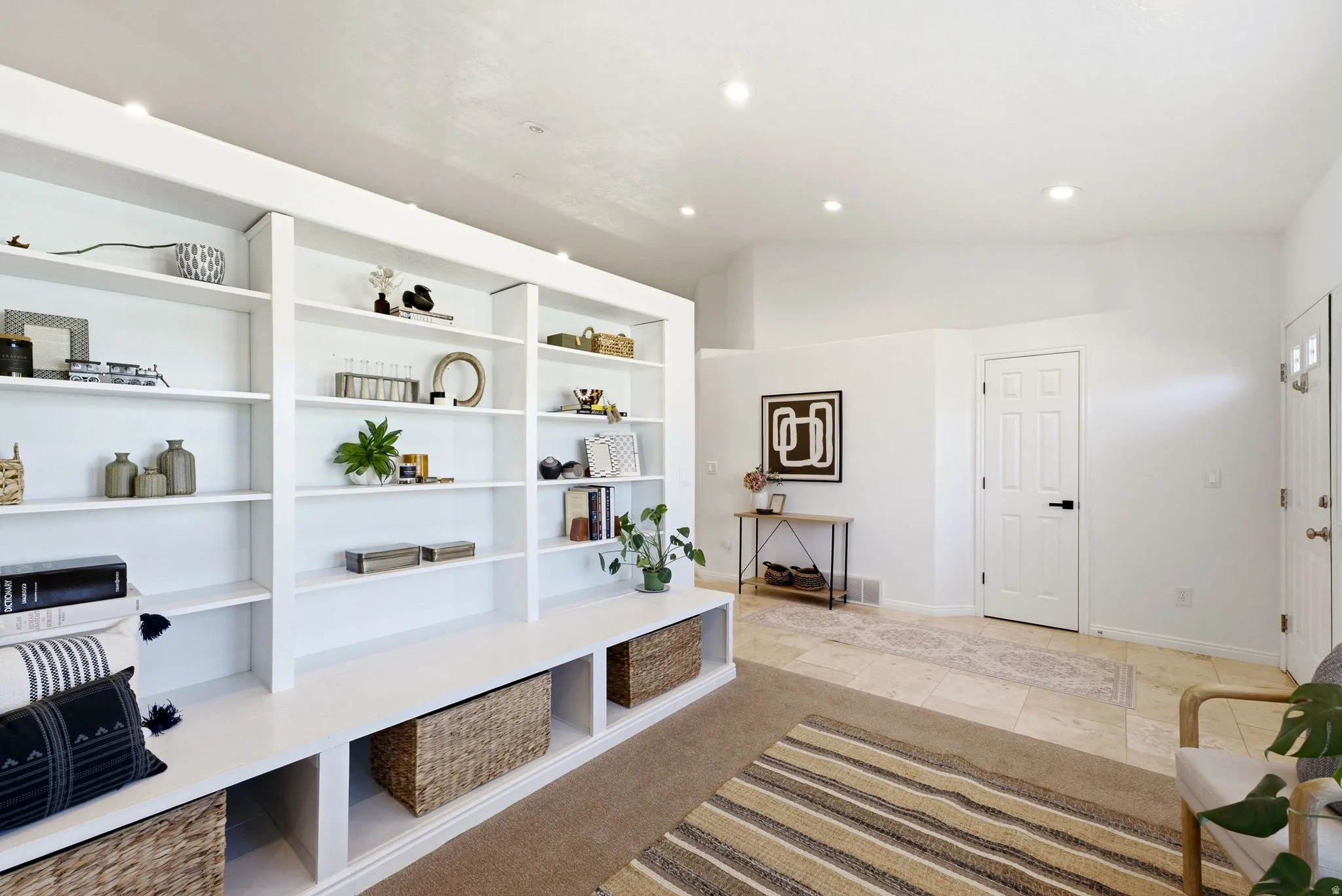 Built-in shelving with storage cubbies, recessed lighting, vaulted ceiling, paneled interior door, and tile flooring