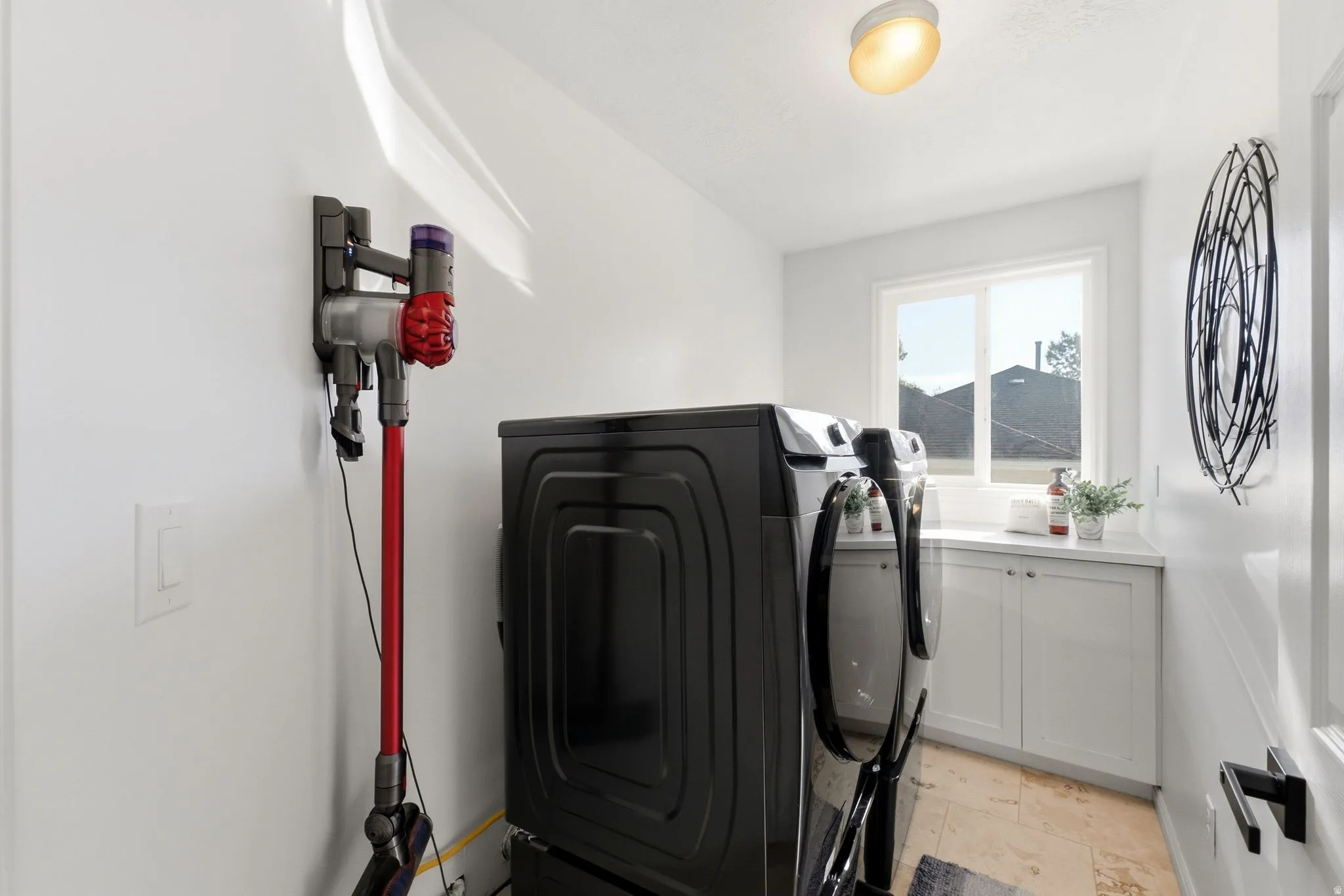 Laundry area featuring white cabinetry, a countertop, a window, and tile flooring