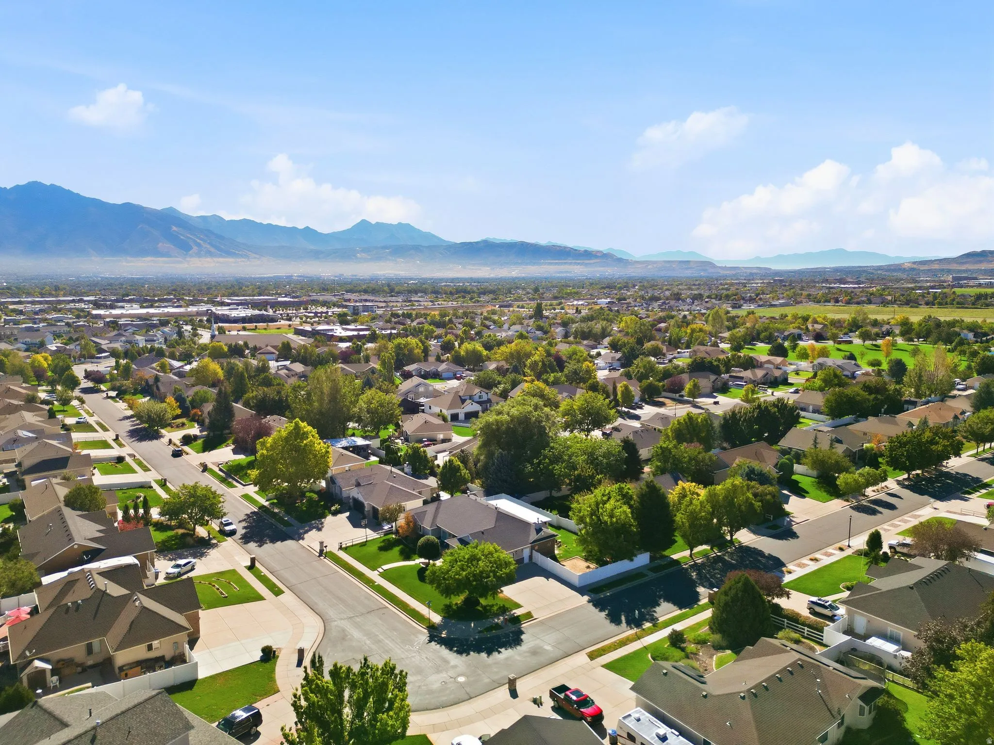 Expansive residential neighborhood with mature trees, green spaces, and mountain scenery