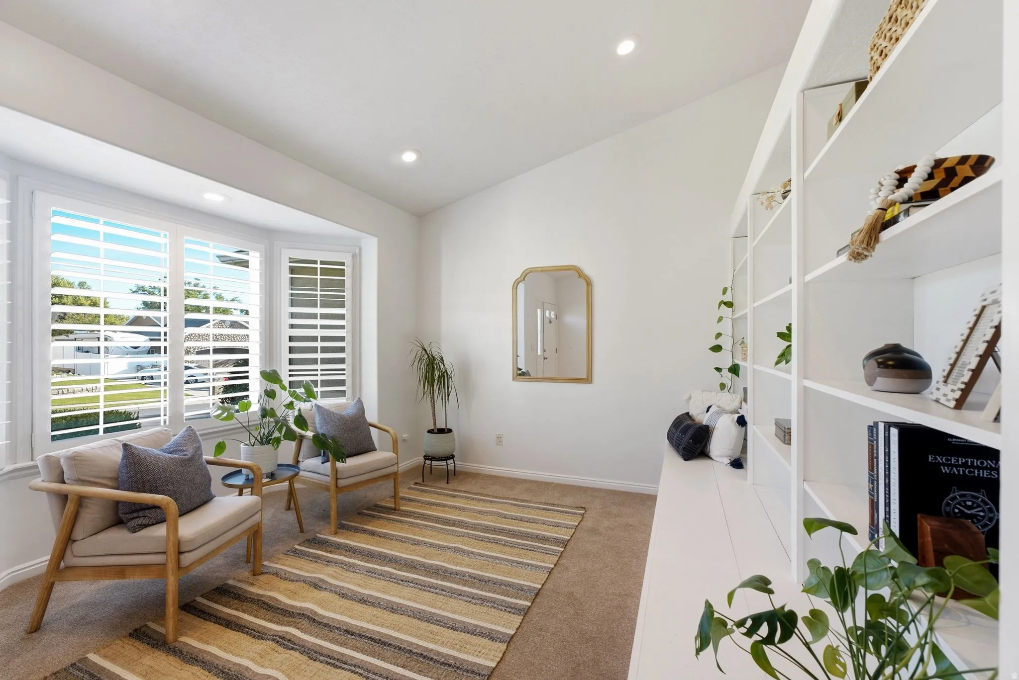 Bay window with plantation shutters, built-in shelving, recessed lighting, and vaulted ceiling