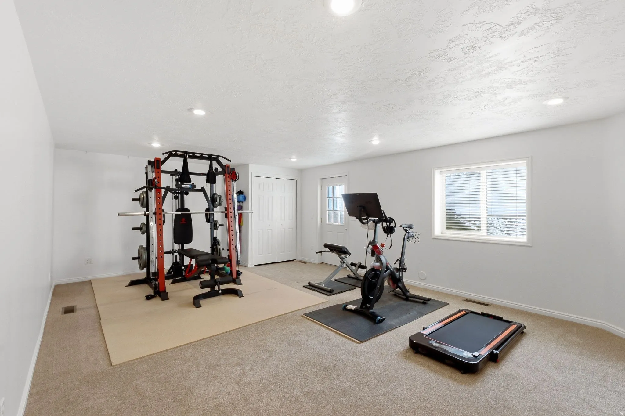 Carpeted room featuring a white door, a window with blinds, and recessed lighting