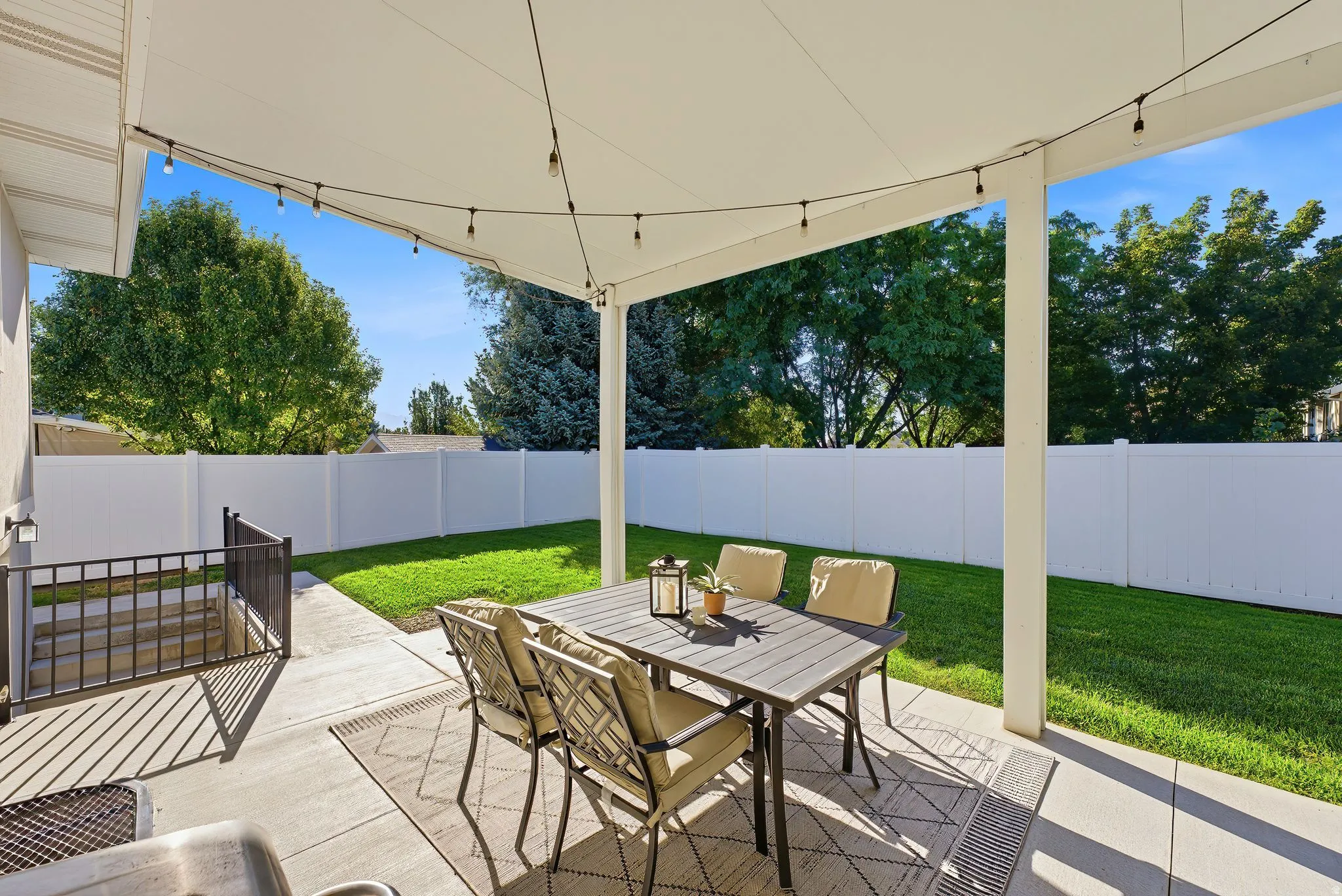 Covered patio with string lighting, concrete flooring, and direct access to a grassy yard