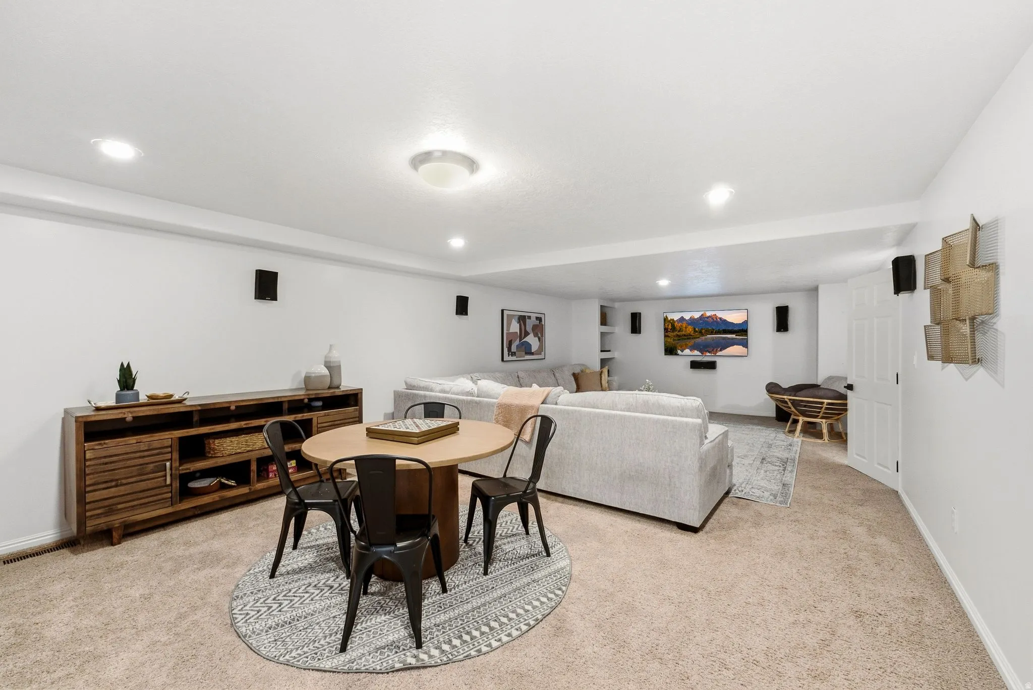 Recessed lighting, perimeter audio speakers, built-in shelving, white walls, and carpet flooring