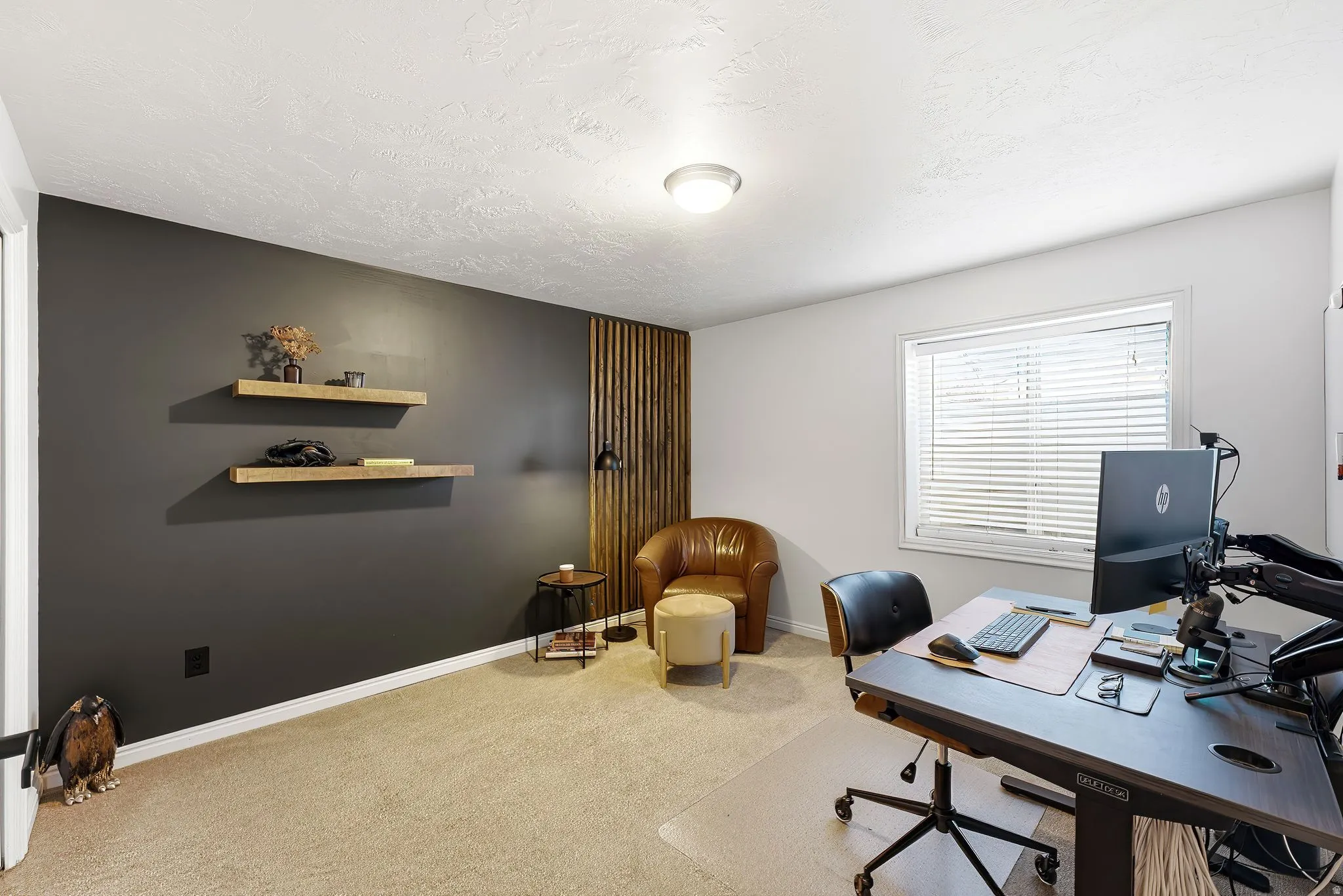 Window with blinds, wall-mounted floating shelves, wood-panel accent wall, carpeted flooring, flush mount ceiling light