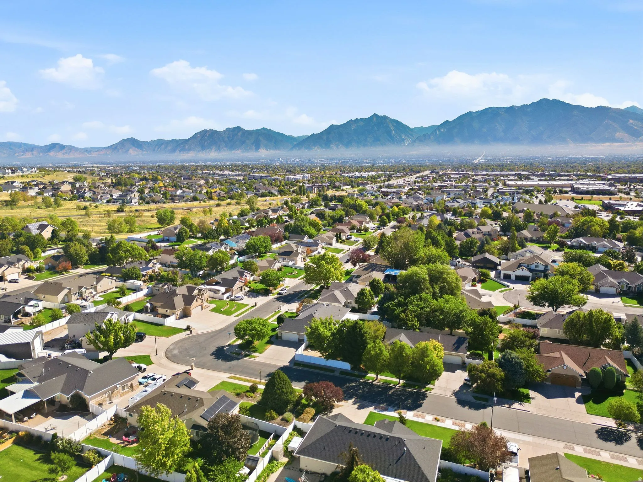 Residential neighborhood with established homes, mature trees, and mountainous scenery