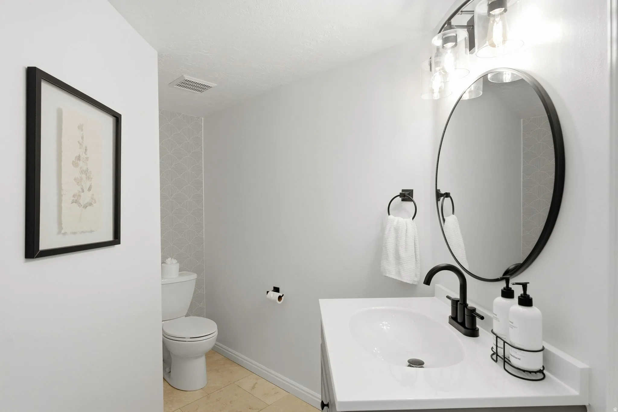 Contemporary vanity with a white countertop and oval sink, matte black faucet, and a round mirror