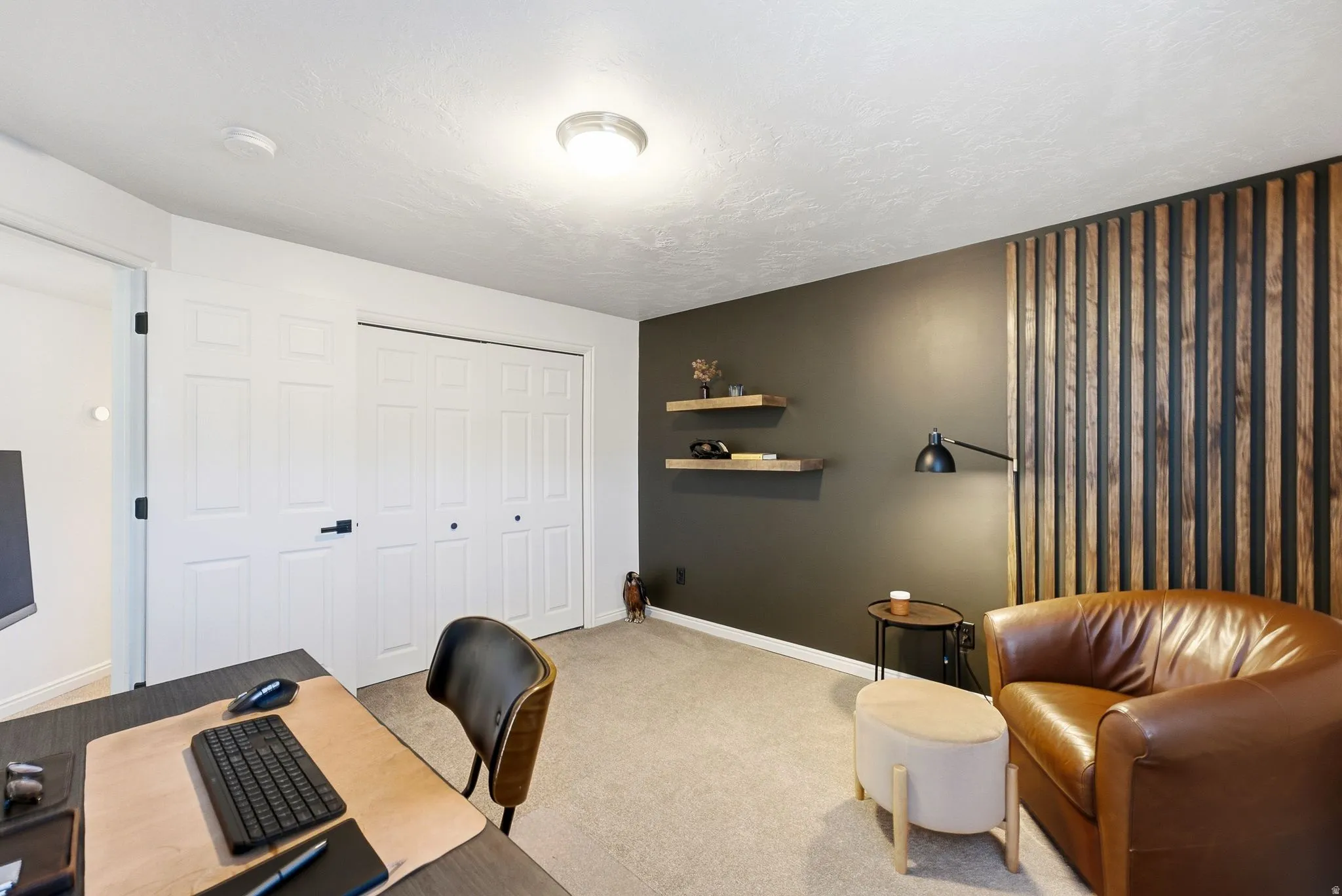 Built-in closet with panel doors, recessed wall shelving, accent wall with vertical wood slat detailing, and neutral tone carpeting