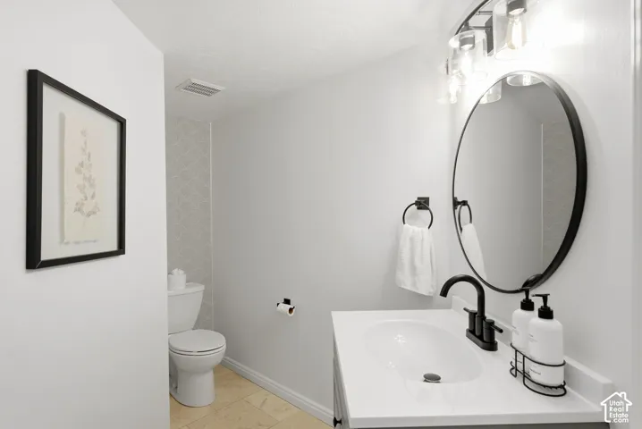 Contemporary vanity with a white countertop and oval sink, matte black faucet, and a round mirror