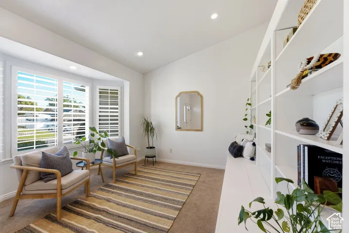 Bay window with plantation shutters, built-in shelving, recessed lighting, and vaulted ceiling