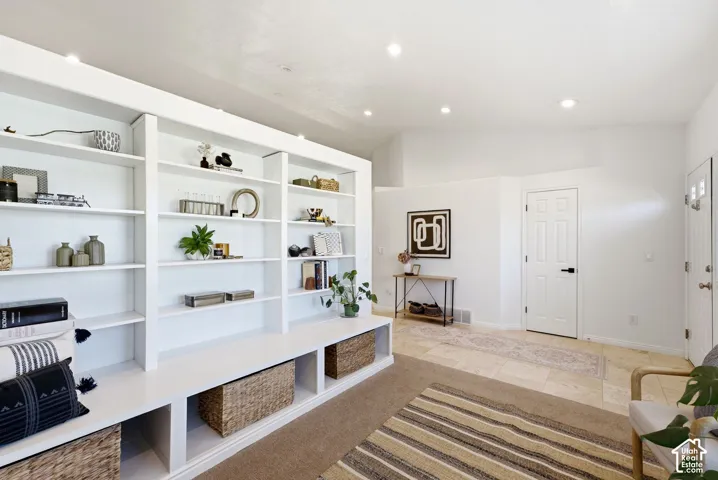 Built-in shelving with storage cubbies, recessed lighting, vaulted ceiling, paneled interior door, and tile flooring