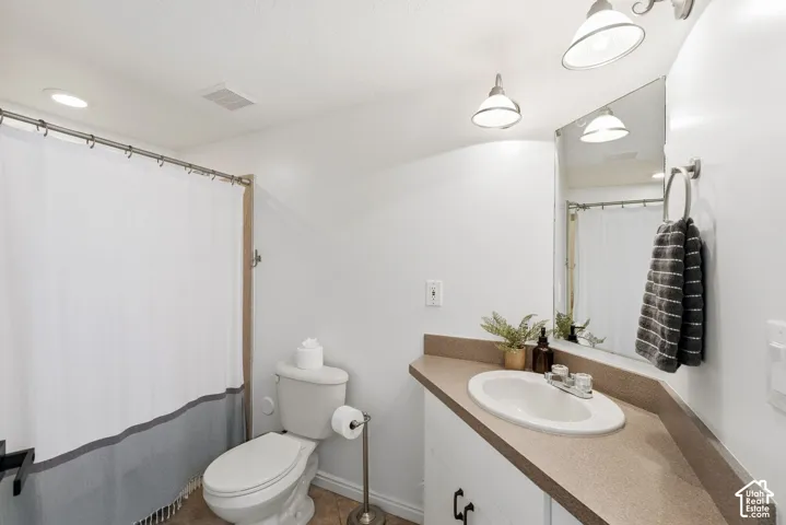 Bathroom featuring a vanity with a drop-in sink, wall-mounted mirror, and overhead lighting