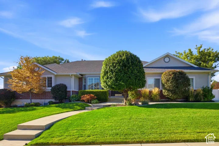 Stucco and brick exterior with a gabled roof, prominent bay window, and concrete walkway