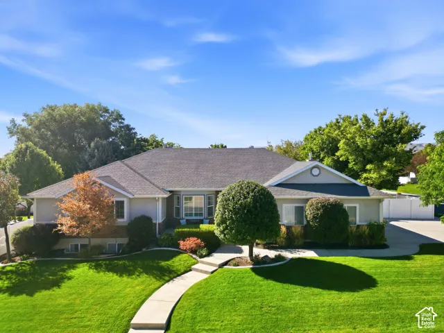 Manicured lawn, mature landscaping, paved driveway, curved walkway, and a multi-level roofline