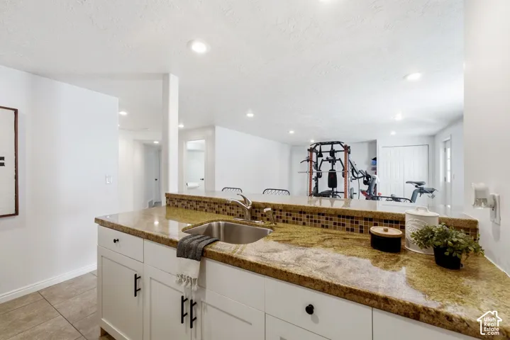 Kitchenette featuring a stainless steel sink, granite-style countertop, mosaic tile backsplash, and recessed lighting