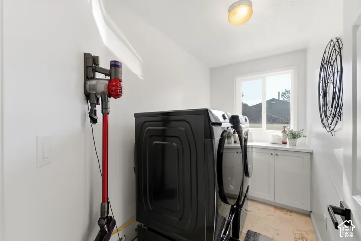 Laundry area featuring white cabinetry, a countertop, a window, and tile flooring