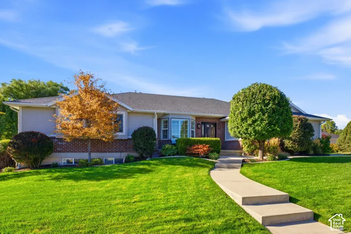 Exterior featuring a bay window, brick and stucco siding, a dark roof, and a concrete pathway