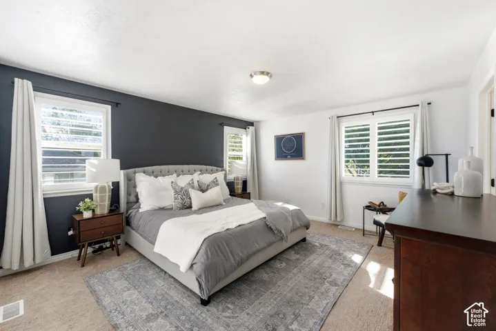 Spacious Primary room featuring white walls and a contrasting accent wall, two windows with white plantation shutters, and a flush mount ceiling light