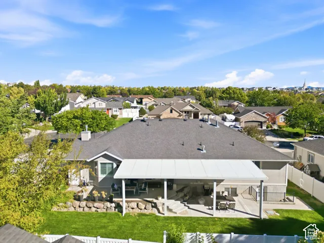 Expansive outdoor patio with a covered section, mature landscaping, and a manicured lawn
