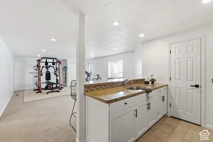 Built-in wet bar with a single-basin sink, mosaic tile backsplash, and white cabinetry