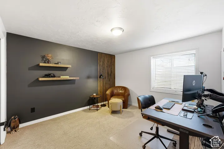 Window with blinds, wall-mounted floating shelves, wood-panel accent wall, carpeted flooring, flush mount ceiling light