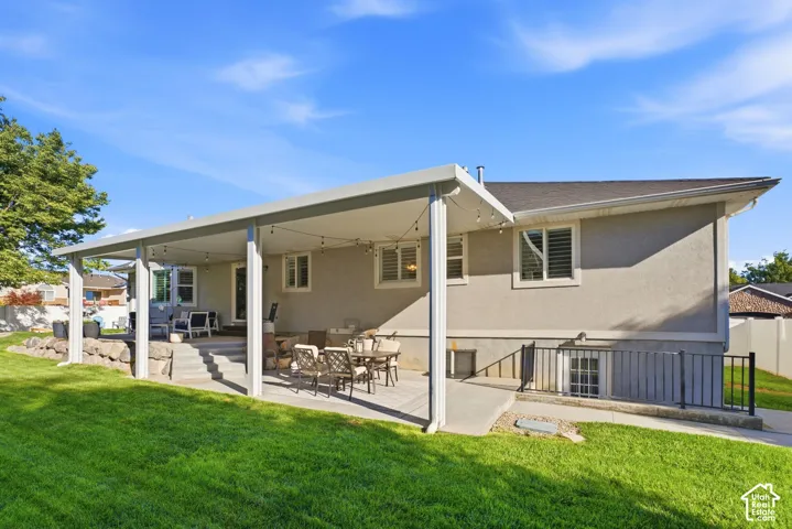 Expansive covered patio with concrete flooring, stucco exterior, and a manicured lawn