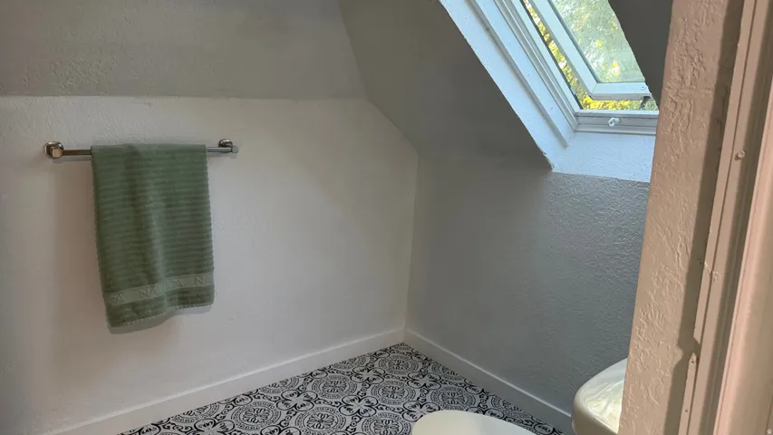 Sloped ceiling architecture, patterned floor tiling, skylight feature, and white wall finishes