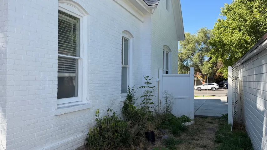 White brick exterior with arched window casings and a white privacy gate
