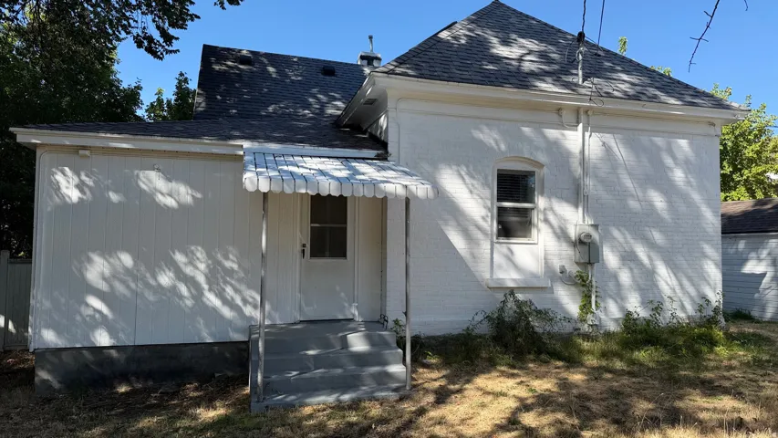 White brick exterior with a dark shingle roof