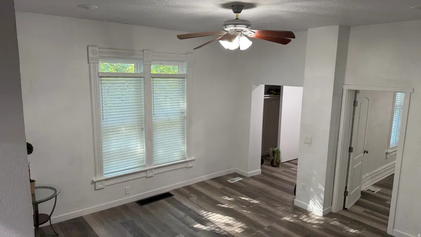 Wood-finish flooring, ceiling fan with integrated lighting, white trim, and white paneled door