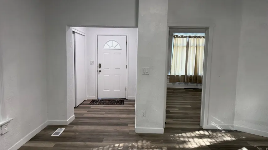 Entryway featuring a paneled door with an arched window, wood-finish flooring, and a built-in closet with sliding doors
