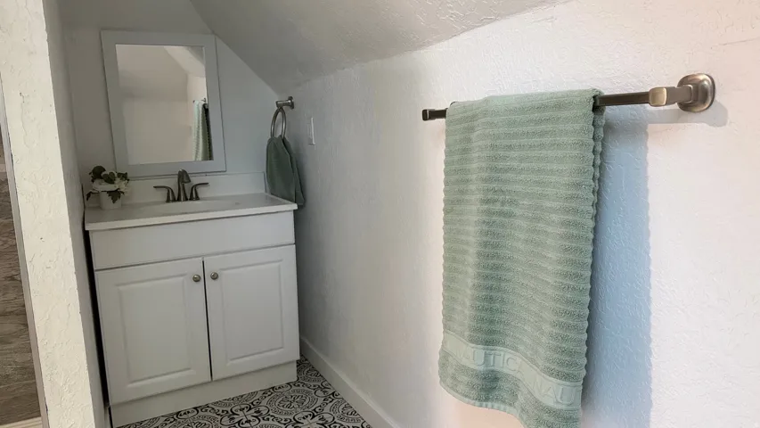 White vanity with under-sink storage, integrated sink, and an attached rectangular mirror