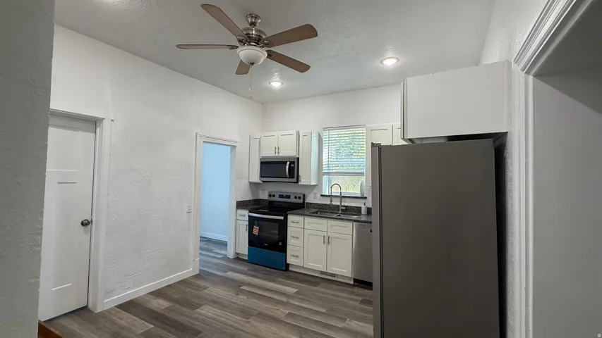 Kitchen featuring wood-finish flooring, recessed lighting, ceiling fan, white cabinetry, and stainless steel appliances