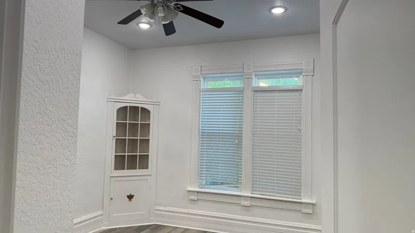 Recessed lighting, ceiling fan with integrated lighting, wood-finish flooring, built-in corner cabinet, and decorative window trim