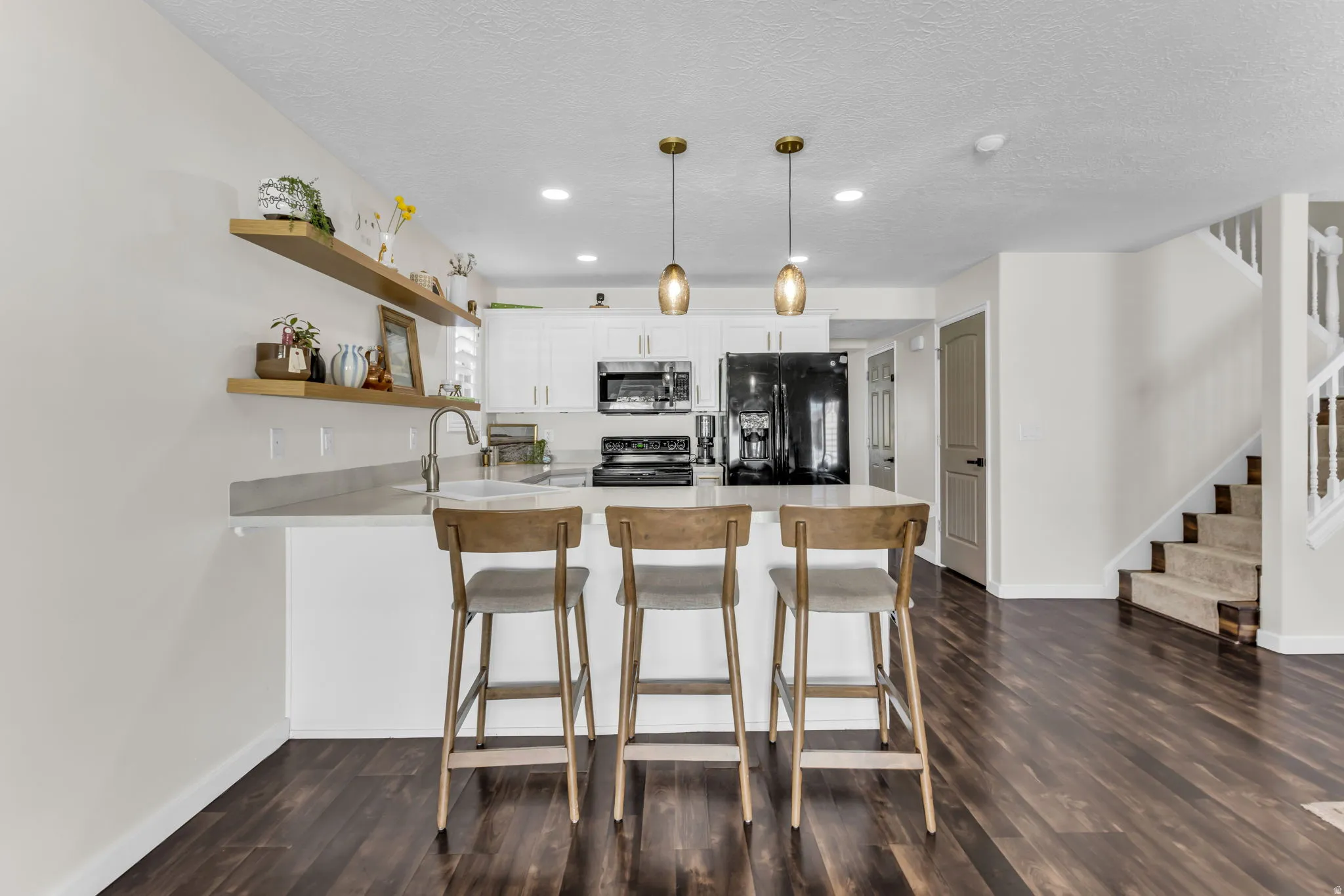 White cabinets, floating shelves, pendant lighting, and black appliances. All appliances included!