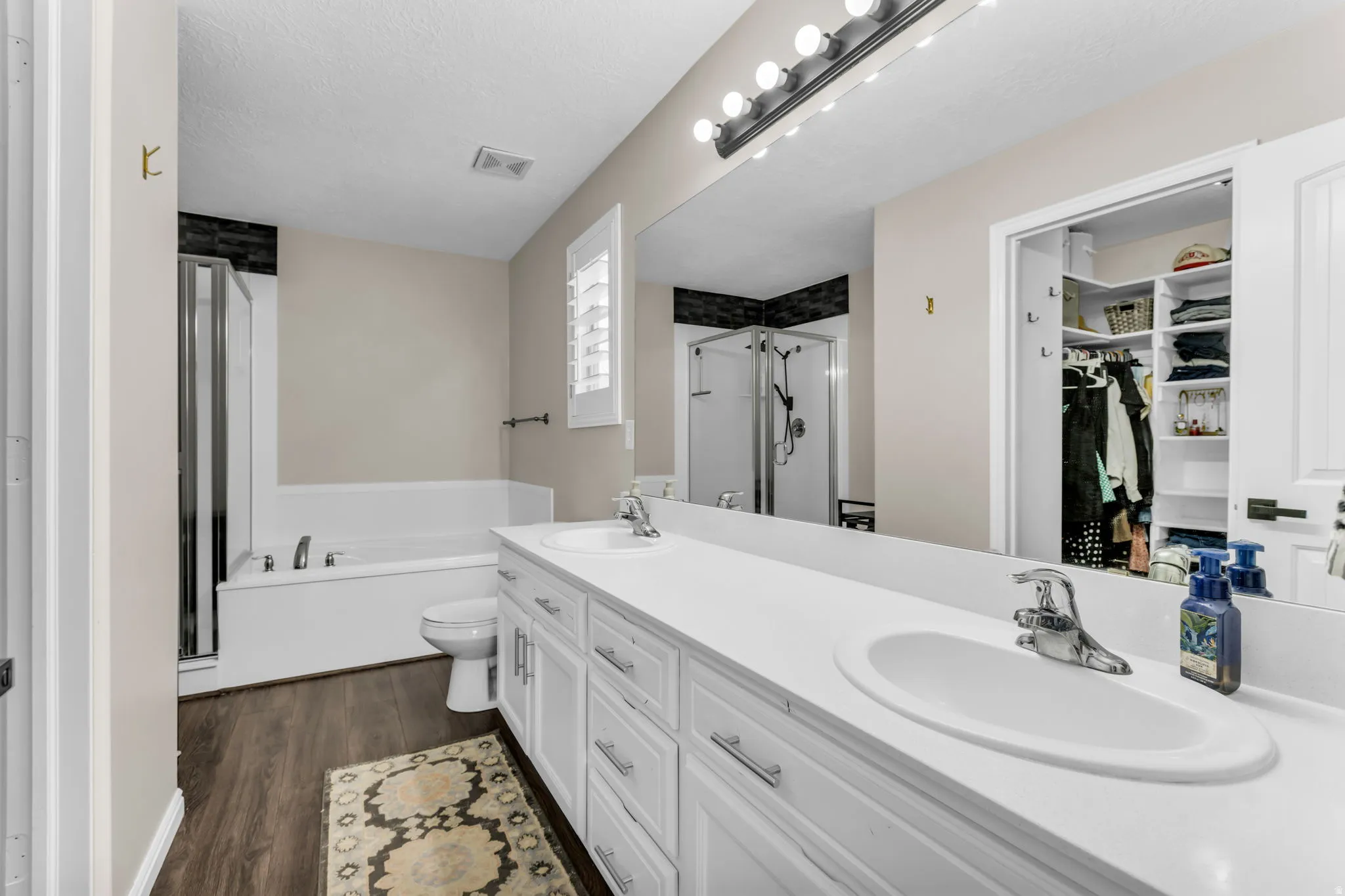 Master bathroom with dual vanity, separate tub and shower, walk in closet