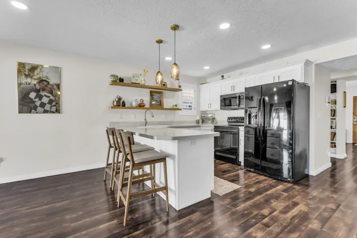 White cabinets, floating shelves, pendant lighting, and black appliances. All appliances included! Sellers willing to include floor allowance